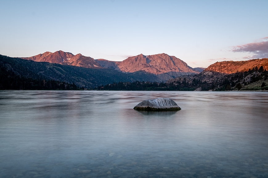 Serene Lake Landscape with Misty Water and Sunlit Mountains