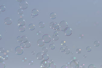 Floating Soap Bubbles with Iridescent Highlights on Soft Blue Background