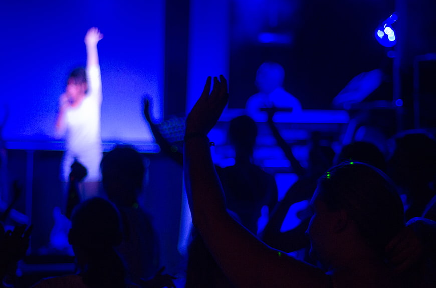 Silhouettes of crowd cheering at blue-lit concert