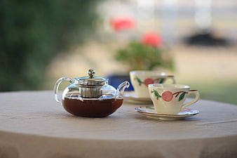 Glass Teapot and Floral Teacups on Outdoor Table