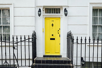 Vibrant yellow front door on white Victorian townhouse facade