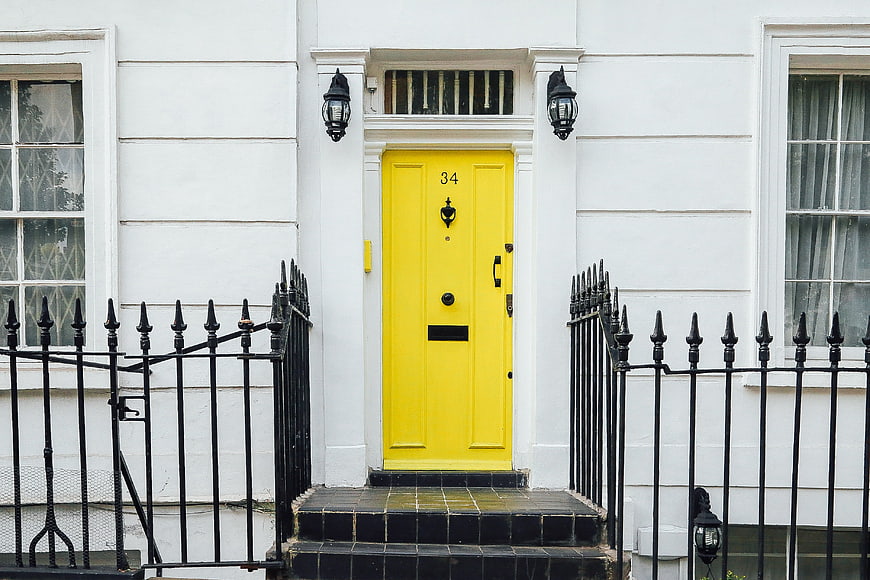 Vibrant yellow front door on white Victorian townhouse facade