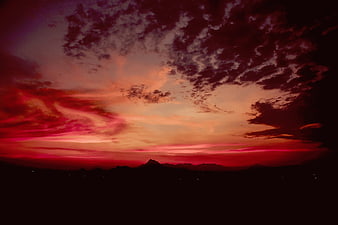 Dramatic red sunset sky with clouds over mountain silhouette