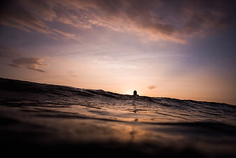 Silhouette of a Surfer Waiting for Waves at Sunset in the Ocean