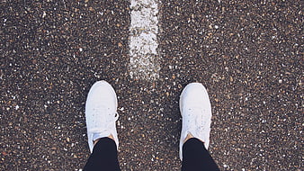 Top View of White Sneakers on Asphalt Road