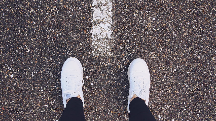 Top View of White Sneakers on Asphalt Road