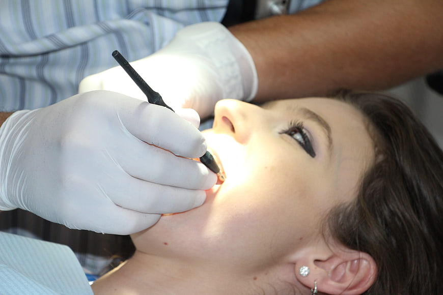 Dentist examining patient teeth with dental tool