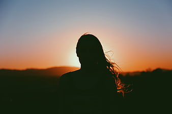 Silhouette of Woman Watching Sunset Over Hills