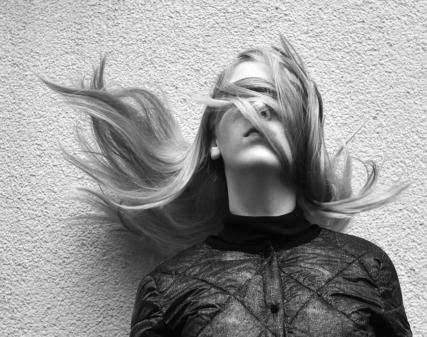 Black and white portrait of woman with windblown hair covering face