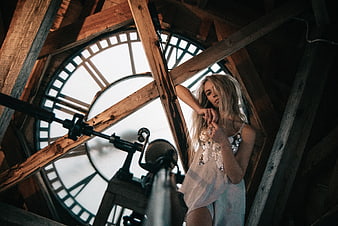 Blonde woman in white dress posing inside rustic clock tower
