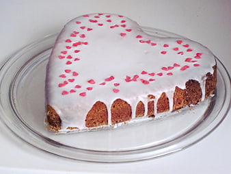 Heart-shaped sponge cake with white icing and pink heart sprinkles