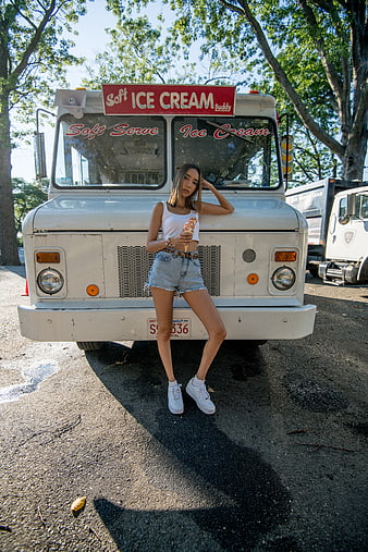 Woman eating ice cream cone in front of retro truck