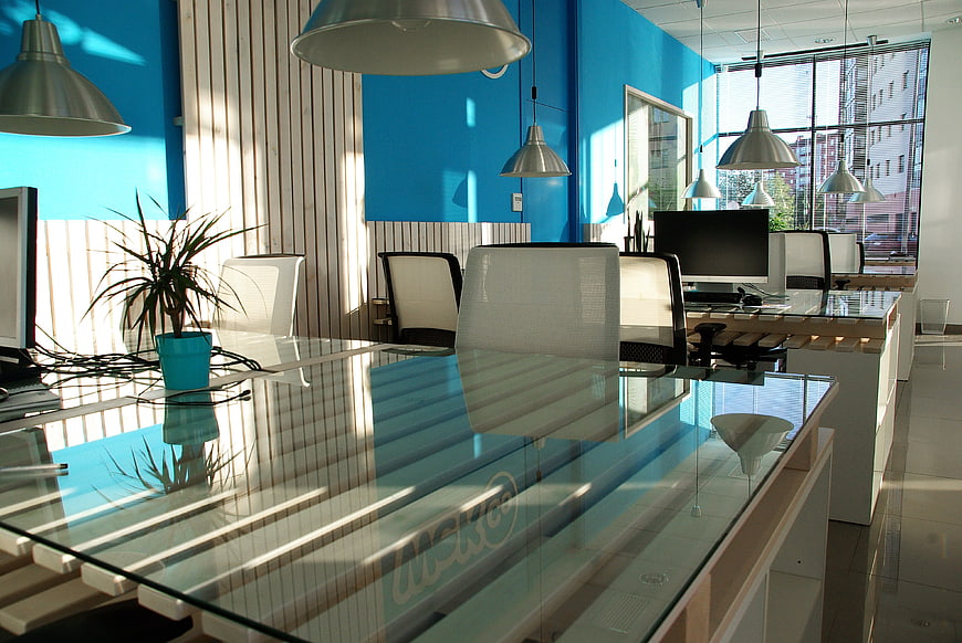 Modern office interior with glass desks and blue walls