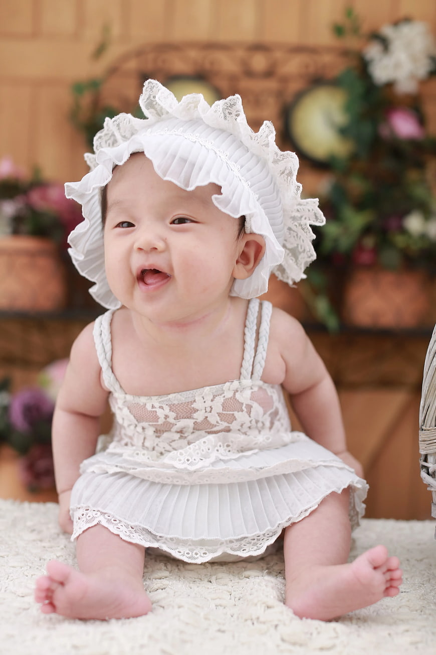 Smiling baby girl in white lace dress and bonnet