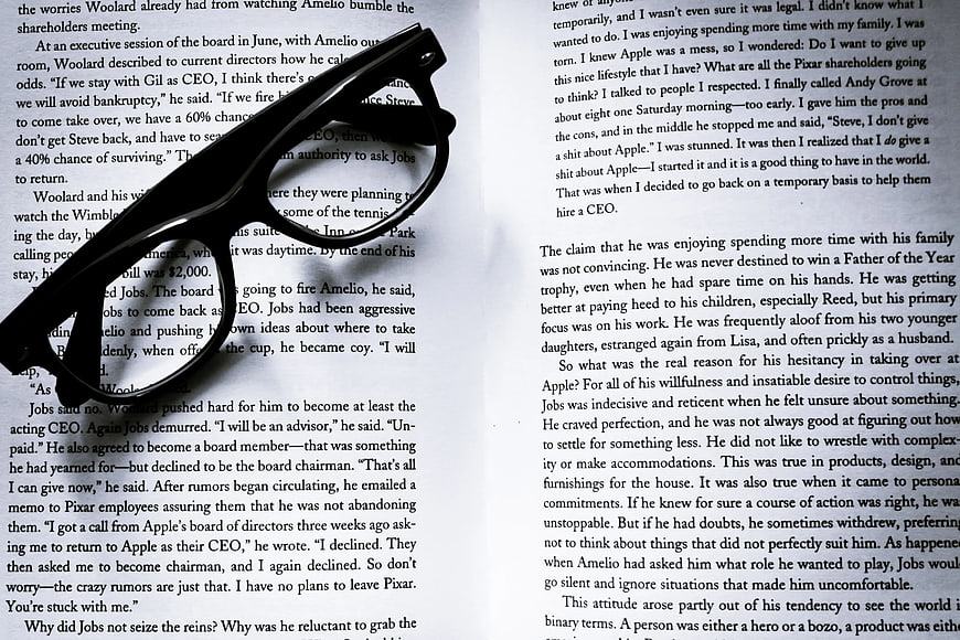 Black eyeglasses resting on open book pages
