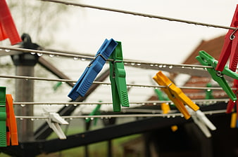 Colorful plastic clothespins on wet clothesline in rain