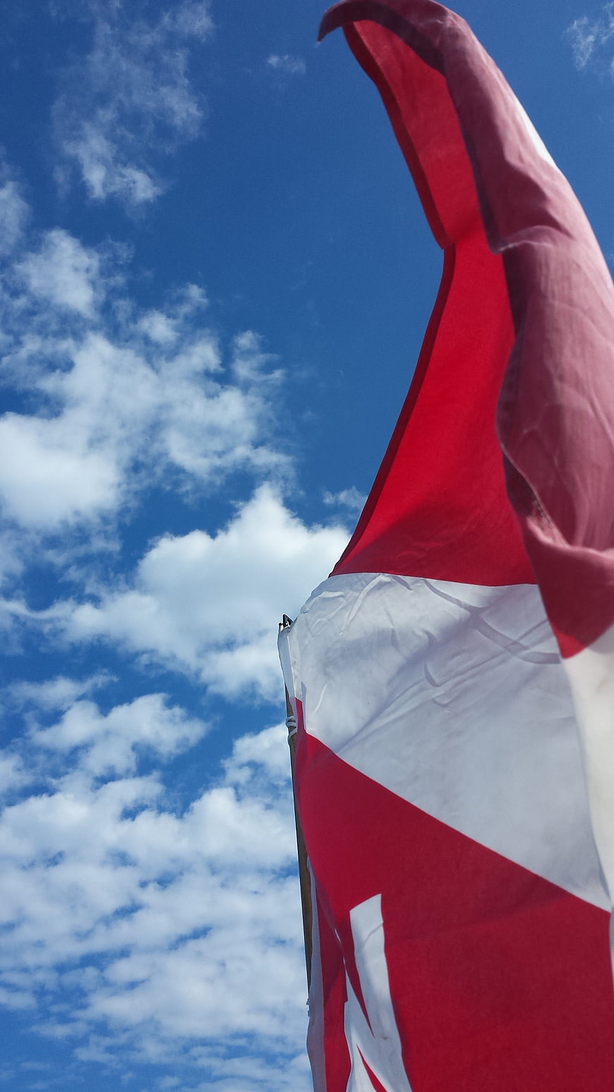 Red and White Flag Waving Against Blue Sky