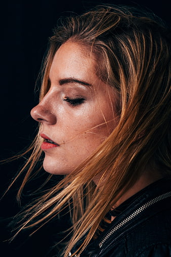 Close-up portrait of woman with windblown hair and leather jacket