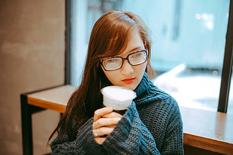Young woman with glasses drinking coffee in a cafe