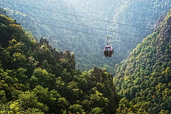 Red Cable Car Suspended Over Lush Mountain Valley