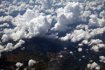 Aerial view of fluffy white clouds over green landscape