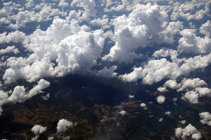 Aerial view of fluffy white clouds over green landscape