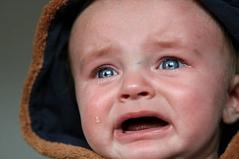 Close-up of crying baby with tears and blue eyes