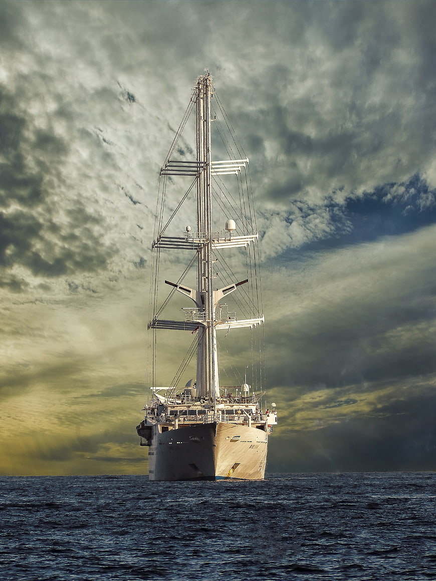 Tall sailing ship mast against dramatic cloudy sky