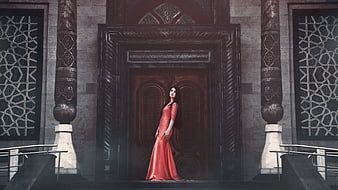 Woman in Red Gown Standing Before Ornate Wooden Door