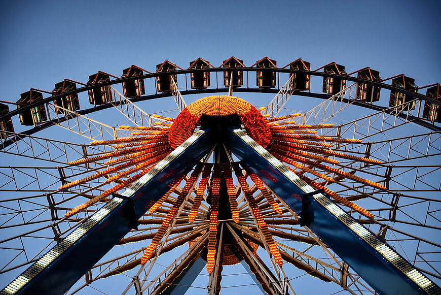 Low angle view of illuminated Ferris wheel against blue sky