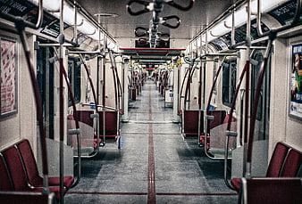 Empty subway car interior with red seats and metal poles