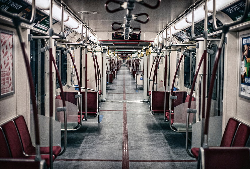 Empty subway car interior with red seats and metal poles