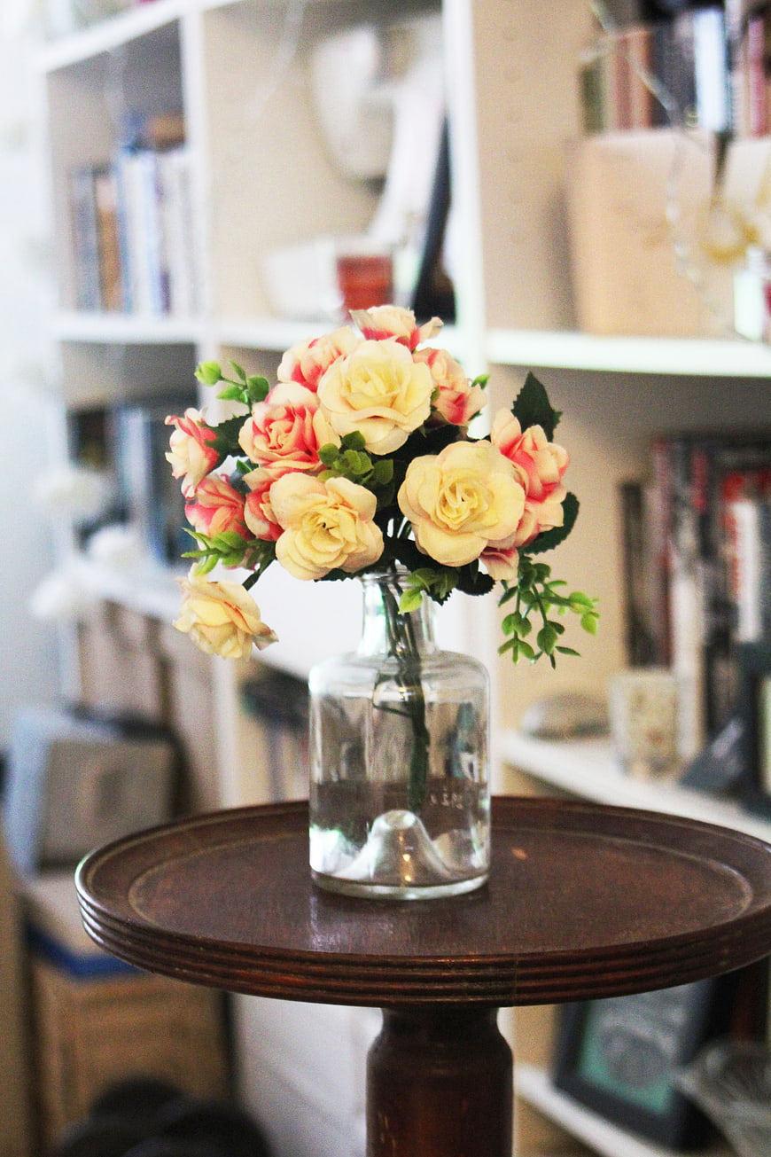 Yellow and pink roses in a glass vase on a wooden table