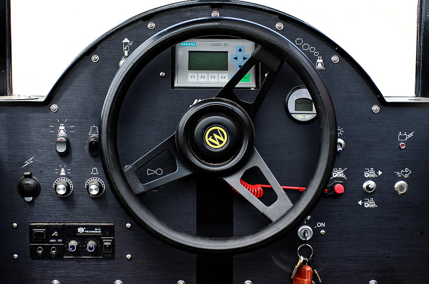 Close-up of black industrial steering wheel and control panel