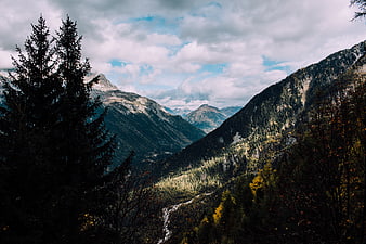 Majestic Mountain Valley with Autumn Trees and Cloudy Sky