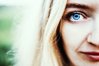 Close-up portrait of woman with striking blue eye and blonde hair