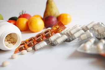 Vitamins and pills with fresh fruits on white background