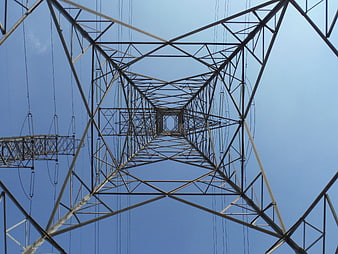 Low angle view of high voltage transmission tower against blue sky