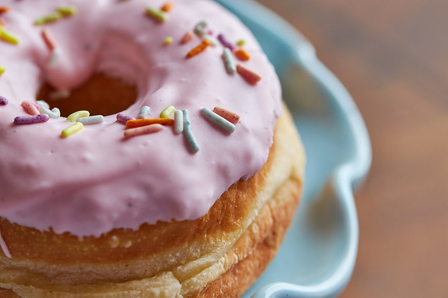 Close-up of pink frosted donut with sprinkles on blue plate