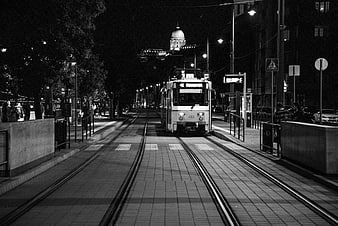 Night view of tram tracks leading to illuminated dome in Budapest