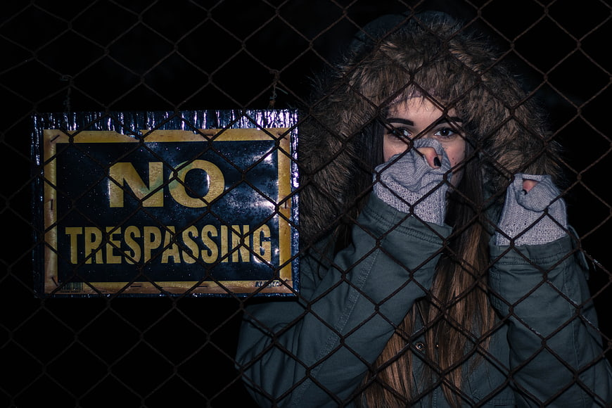 Woman behind chain-link fence with no trespassing sign