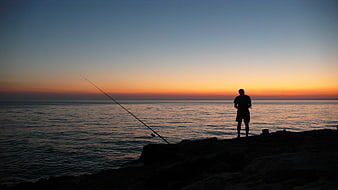 Silhouette of Man Fishing at Sunset on Ocean