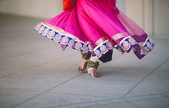 Bare feet of woman dancing in vibrant pink traditional skirt