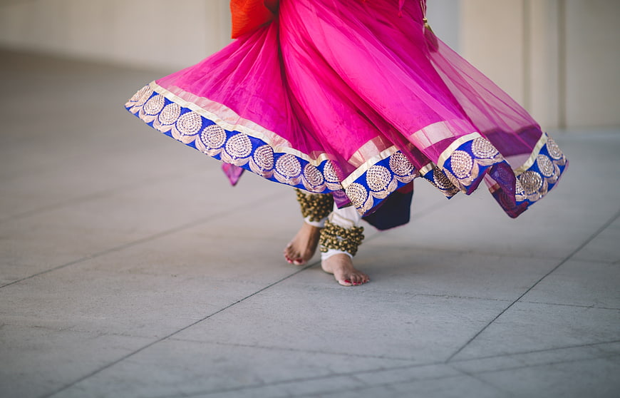 Bare feet of woman dancing in vibrant pink traditional skirt