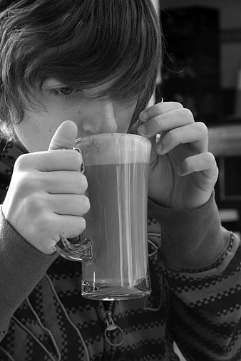Boy drinking coffee from glass mug in black and white