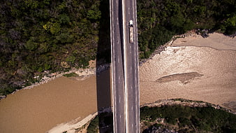 Aerial view of truck crossing bridge over muddy river