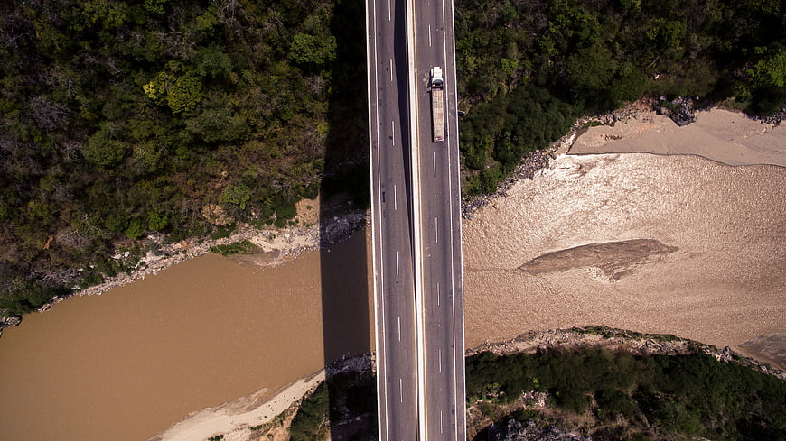 Aerial view of truck crossing bridge over muddy river
