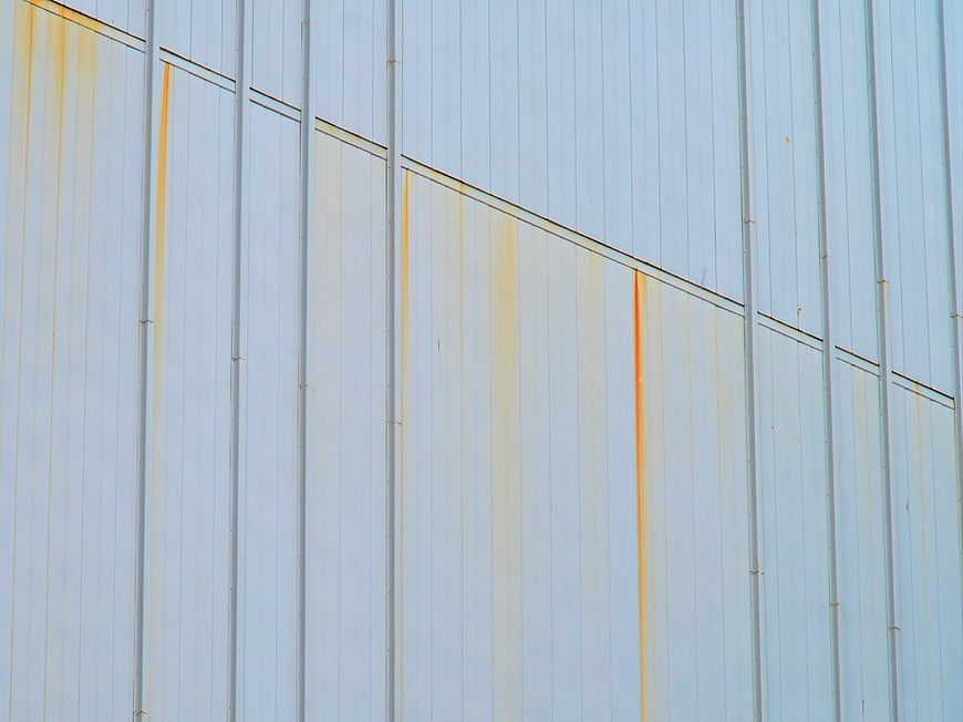 Abstract Rust Streaks on White Corrugated Metal Wall
