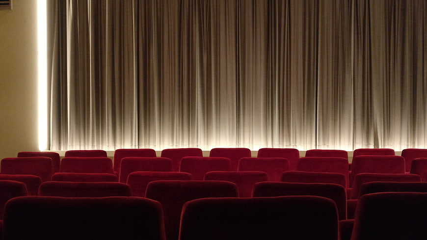 Empty Cinema Hall with Red Seats and Stage Curtain