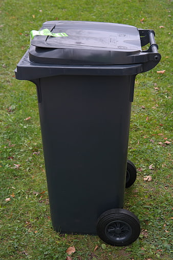 Black wheeled waste bin on green grass